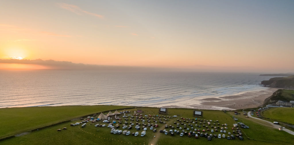 Cars parked atop a beautiful Cornish Cornish clifftop at sunset for Drive In Cinema